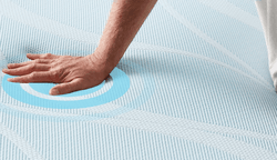 A hand pressing on the cooling cover of a breeze mattress